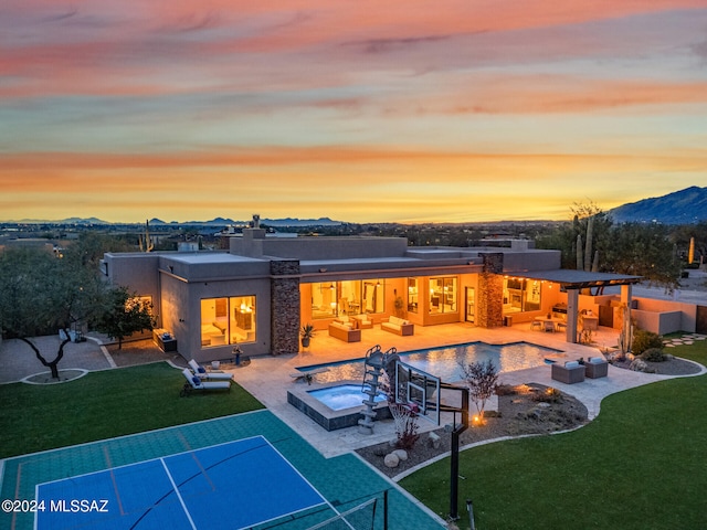 back house at dusk featuring a lawn, outdoor lounge area, a patio area, and a mountain view