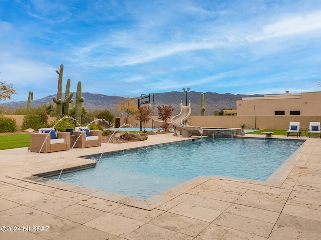 view of swimming pool featuring pool water feature, a mountain view, a water slide, and a hot tub