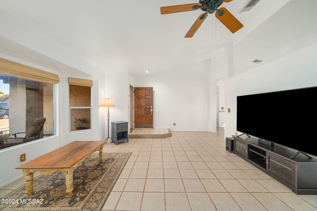 living room featuring ceiling fan, light tile patterned flooring, a wood stove, and vaulted ceiling