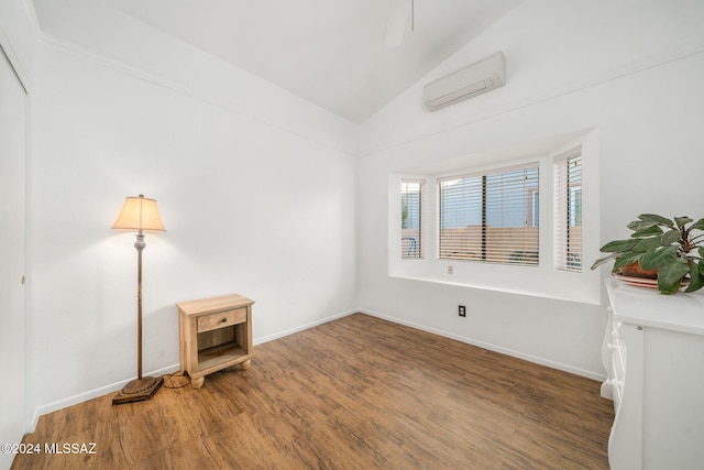 unfurnished room with a wall mounted AC, hardwood / wood-style floors, and vaulted ceiling