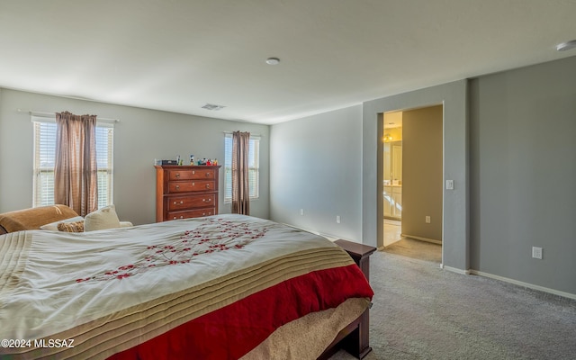 bedroom featuring light colored carpet and ensuite bath