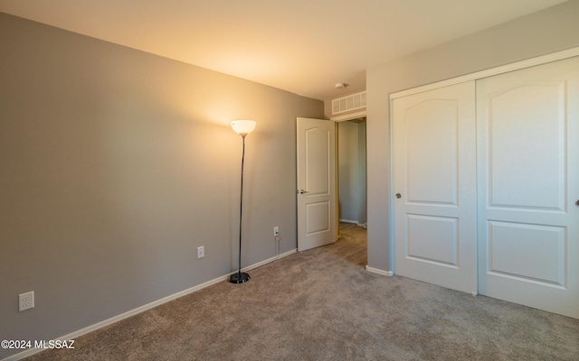 unfurnished bedroom featuring light carpet and a closet