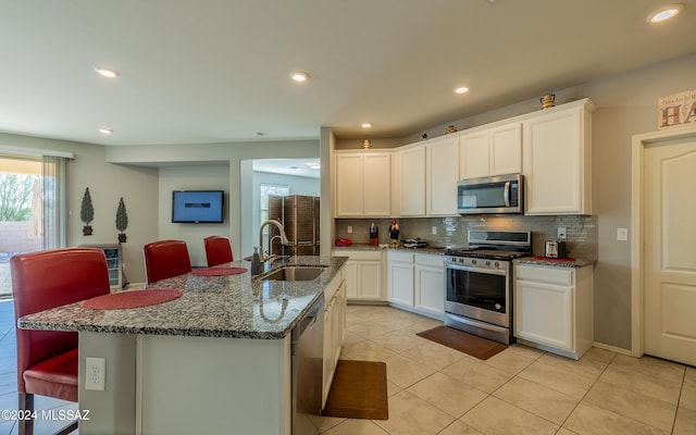 kitchen featuring a center island with sink, white cabinets, stainless steel appliances, and sink