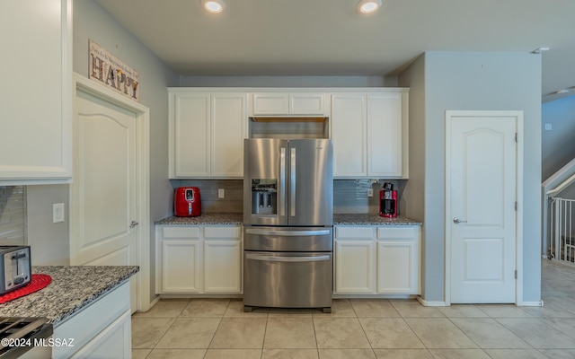 kitchen with white cabinets, stainless steel fridge with ice dispenser, backsplash, and dark stone countertops