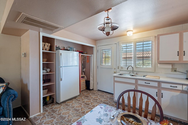 kitchen with sink, white cabinets, a textured ceiling, and white fridge