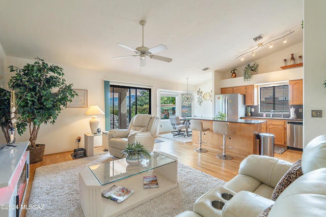 living room with ceiling fan, light hardwood / wood-style flooring, vaulted ceiling, and sink