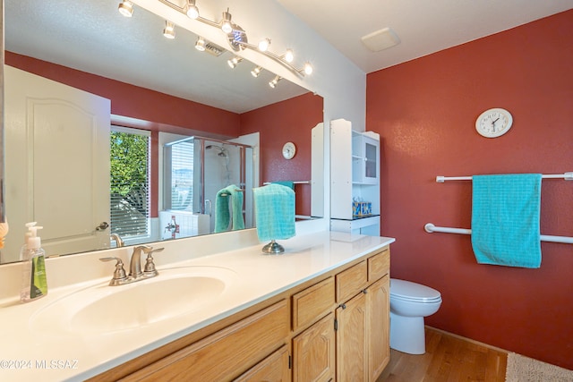 bathroom featuring toilet, hardwood / wood-style floors, vanity, and walk in shower