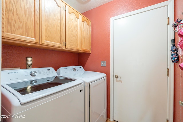 washroom with cabinets, washer and dryer, and a textured ceiling