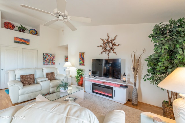 living room featuring ceiling fan, light wood-type flooring, and vaulted ceiling