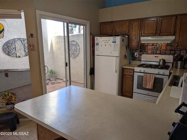 kitchen with backsplash, light tile patterned floors, and white appliances