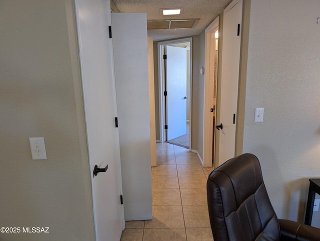 corridor with light tile patterned floors and a textured ceiling