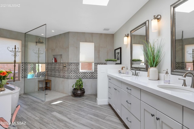 bathroom with a sink, visible vents, walk in shower, and a skylight