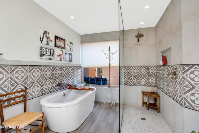 bathroom with tile walls, a soaking tub, recessed lighting, and a walk in shower