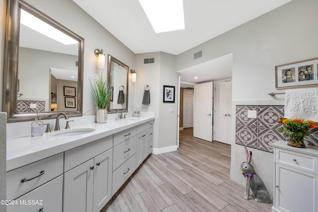 full bath featuring a sink, visible vents, and wood finished floors