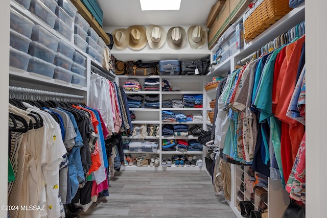 spacious closet with a skylight and wood finished floors