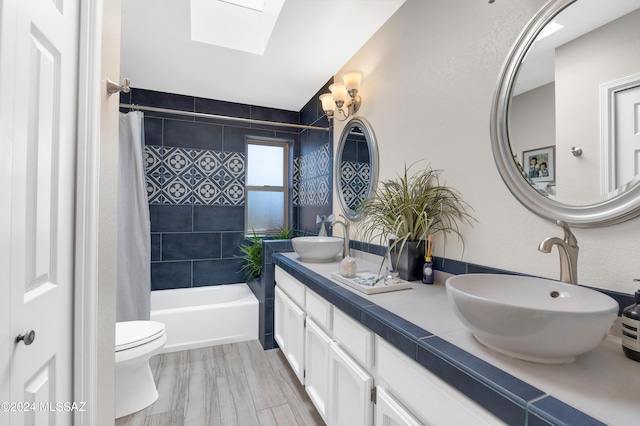 full bathroom featuring wood finished floors, a skylight, shower / bath combo with shower curtain, and a sink