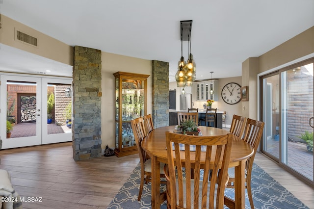 dining area featuring french doors, visible vents, light wood finished floors, and a chandelier