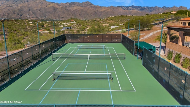 view of sport court with a mountain view and fence