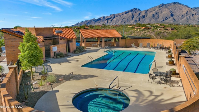 community pool featuring a mountain view, a patio, a community hot tub, and fence