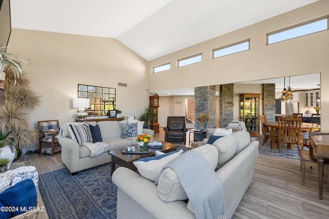 living room featuring visible vents, high vaulted ceiling, and wood finished floors