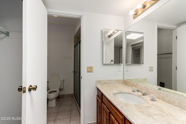 bathroom featuring a shower stall, vanity, tile patterned floors, toilet, and baseboards