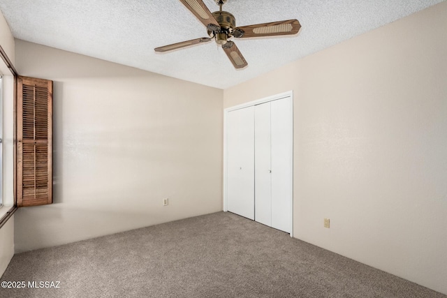 unfurnished bedroom with a closet, a ceiling fan, carpet floors, and a textured ceiling