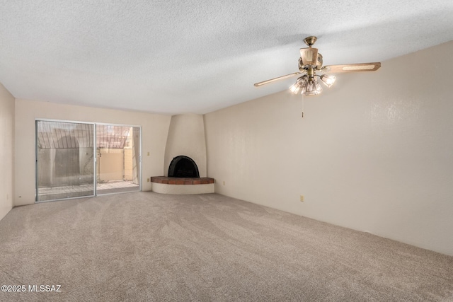 unfurnished living room with a large fireplace, carpet flooring, a ceiling fan, and a textured ceiling