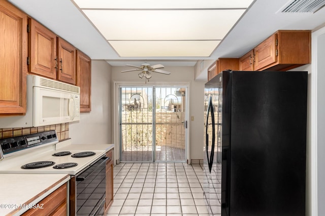 kitchen featuring white microwave, visible vents, light countertops, range with electric stovetop, and freestanding refrigerator
