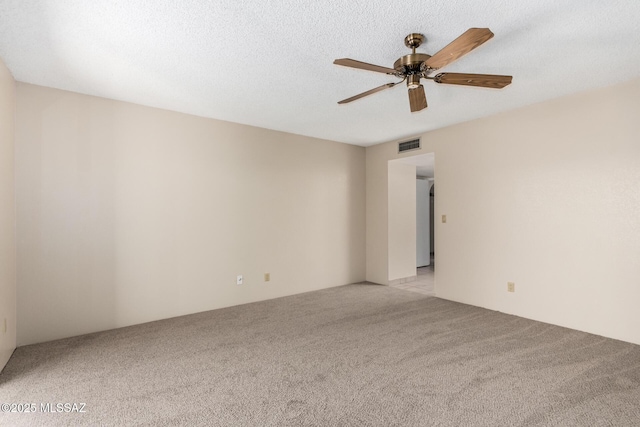 spare room featuring visible vents, a ceiling fan, and light carpet
