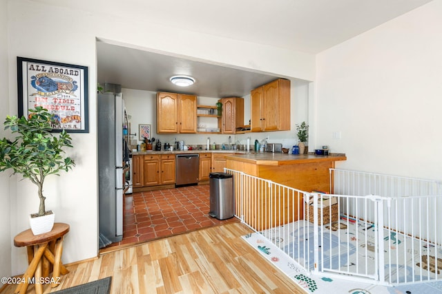 kitchen featuring sink, wood-type flooring, tile counters, and stainless steel appliances