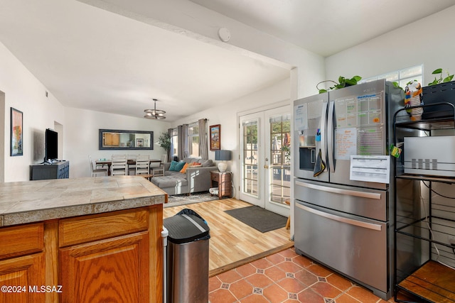 kitchen featuring lofted ceiling, a notable chandelier, dark wood-type flooring, stainless steel fridge, and french doors