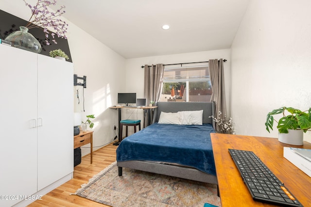 bedroom with light wood-type flooring and vaulted ceiling