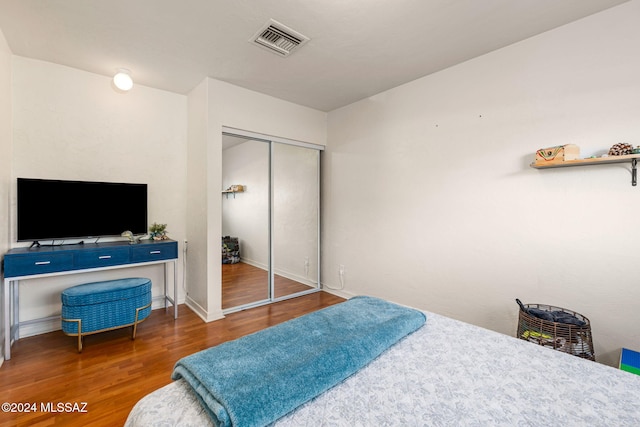 bedroom with dark wood-type flooring and a closet