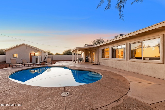 pool at dusk featuring a patio area