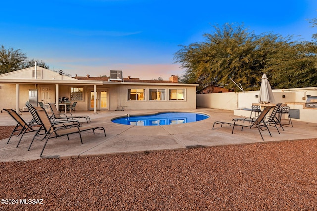 pool at dusk featuring a patio area and a grill
