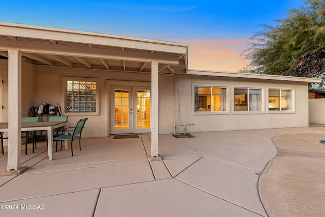 back house at dusk featuring a patio area and french doors