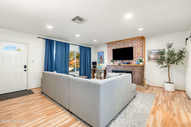living room with a brick fireplace and light hardwood / wood-style flooring