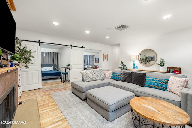 living room with a barn door and hardwood / wood-style flooring