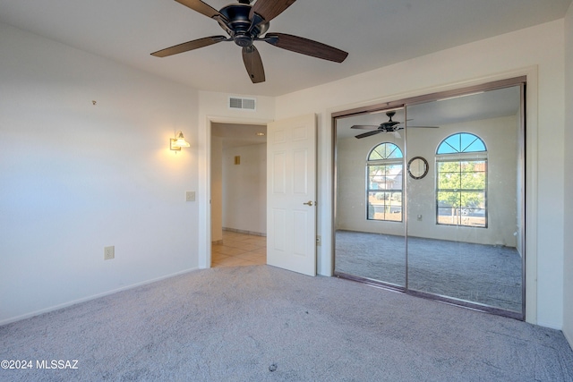 unfurnished bedroom with ceiling fan, light colored carpet, and a closet