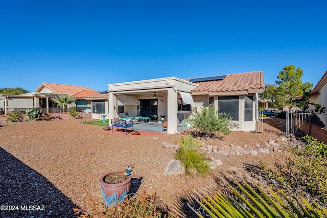 back of property with a patio area, ceiling fan, and solar panels