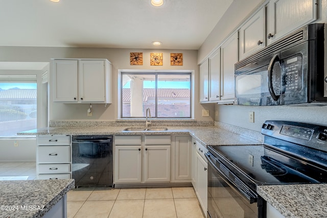 kitchen with light stone countertops, white cabinetry, sink, light tile patterned flooring, and black appliances