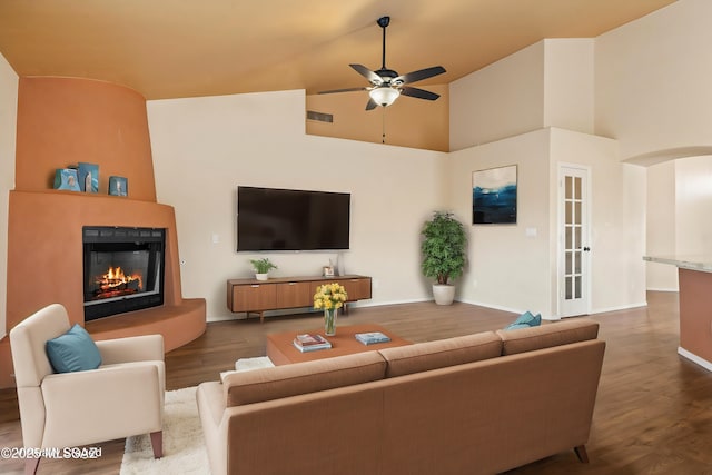 living room with hardwood / wood-style flooring, ceiling fan, and a towering ceiling