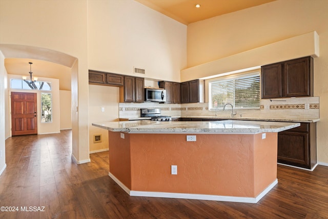 kitchen with a healthy amount of sunlight, appliances with stainless steel finishes, a center island, and backsplash