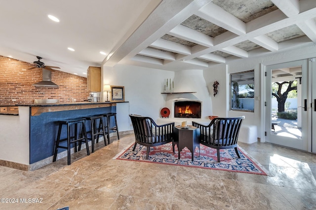 interior space featuring ceiling fan, a fireplace, beamed ceiling, and brick wall