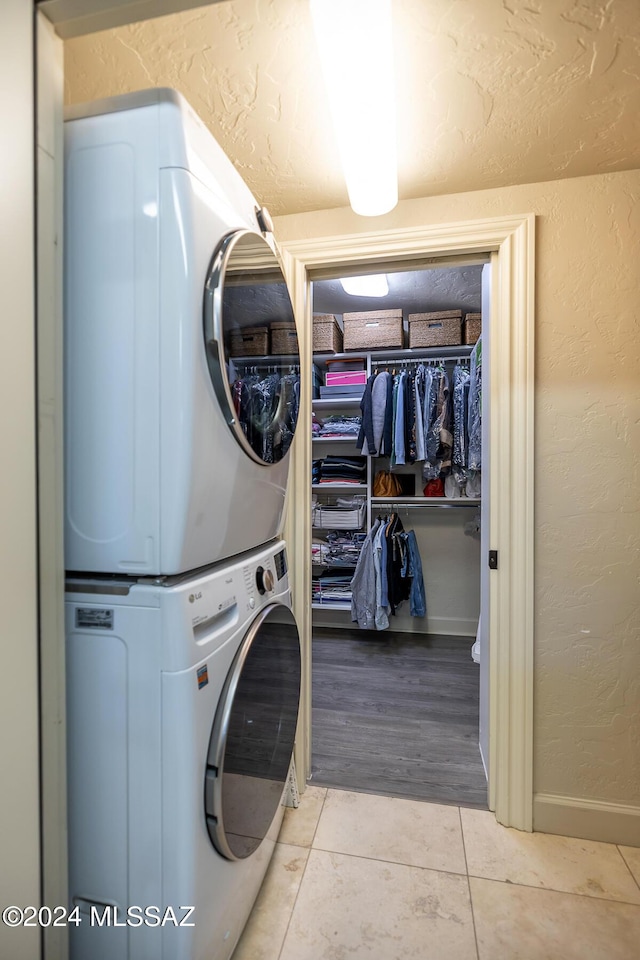 laundry area with light tile patterned flooring and stacked washing maching and dryer