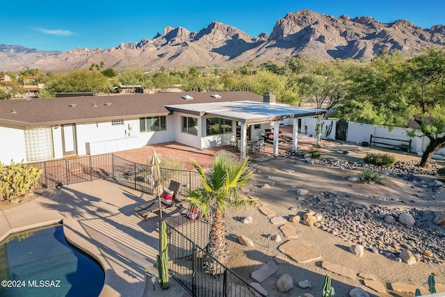 back of house with a fenced in pool, a mountain view, and a patio