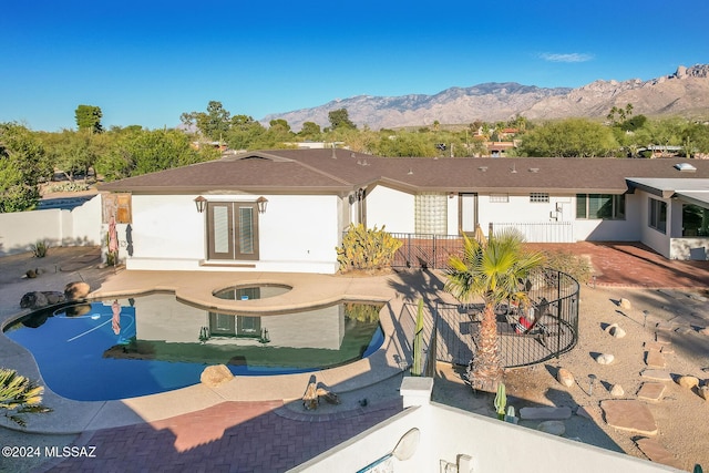 back of property with a mountain view, a fenced in pool, a patio, and french doors