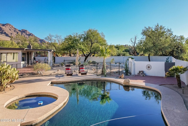 view of swimming pool with a mountain view, a patio, and an in ground hot tub