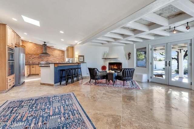 interior space featuring beam ceiling, ceiling fan, french doors, and brick wall