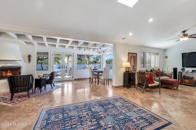 living room featuring ceiling fan, french doors, beamed ceiling, and a healthy amount of sunlight